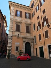 Fototapeta na wymiar Red Car Beside Italian Building