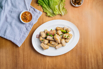 Stir Fried yam in a dish with chili sauce, and king's salad leaf top view on wooden background