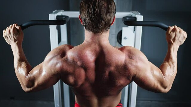 4K Caucasian man athletic workout exercise pulling up body weight lifting machine at fitness club. Male bodybuilder do body building muscle weight training at sport gym. Health care motivation concept