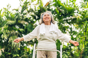 Portrait of happy senior old adult elderly asia women smiling standing and stretch her arms relax and enjoy with nature feeling breath fresh clean air in green park.Healthcare
