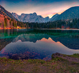 Astonishing morning view of Fusine lake. Superb autumn sunrise in Julian Alps with Mangart peak on background, Province of Udine, Italy, Europe. Beauty of nature concept background.