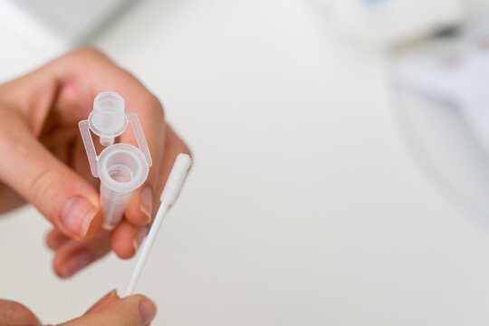 Hands holding Covid-19 rapid antigen test kit tube and cotton swab. Rapid diagnostic self-testing at home
