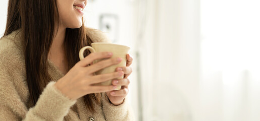 Portrait of smiling happy cheerful beauty pretty asian woman relaxing drinking and looking at cup of hot coffee or tea.Girl felling enjoy having breakfast in holiday morning vacation on bed at home