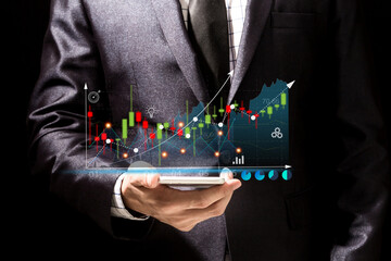 Success Businessman in elegant black suit use digital smartphone looking at screen progress of business financial investment data graph and chart business growth increase