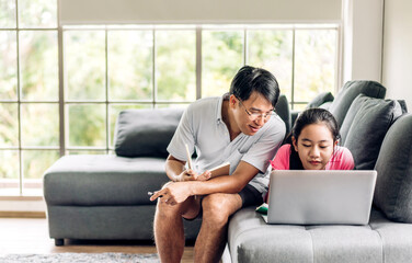 Father and asian kid little girl learn and look at laptop computer reviewing lesson study with online education e-learning.student look for educational knowledge in homeschool at home.Education