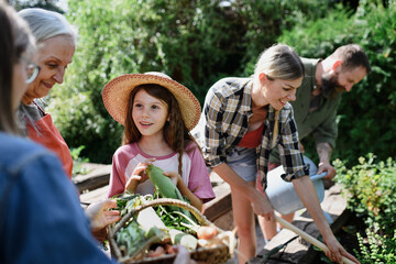 Happy farmers family working with garden tools outdoors at community farm.