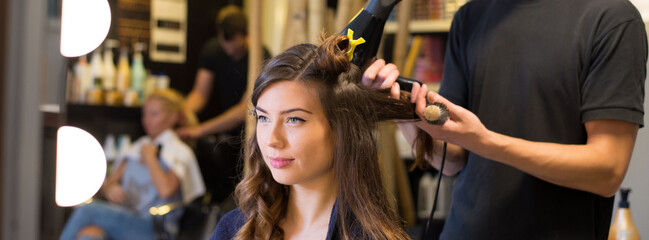 Woman getting new hairstyle done by hairdresser in the modern hair salon.