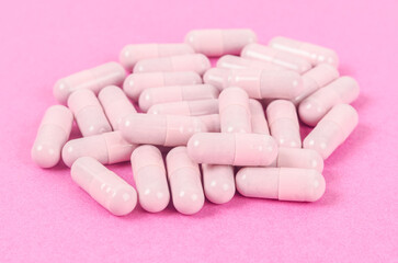 Pink capsule pills on pink.