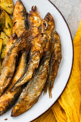 Hearty dinner, baked potatoes with dill and flour-fried capelin close up