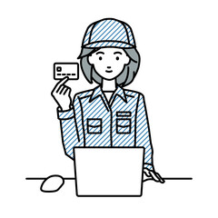 デスクで座ってPCを使いながらクレジットカードを手に持っている作業員の女性