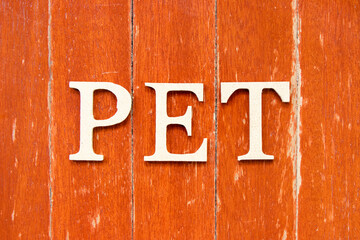 Alphabet letter in word PET (animal or abbreviation of polyethylene terephthalate) on old red color wood plate background