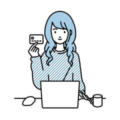 デスクで座ってPCを使いながらクレジットカードを手に持っているリモートワークの女性