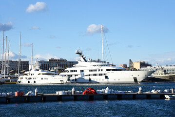 Yachts and motor boats in La Marina de Valencia, Spain. Luxury yacht and fishing motorboat in yacht club at Mediterranean Sea. Skiff and Sailboat in port. Yachting and sailing sport. Quai at ​Dock.