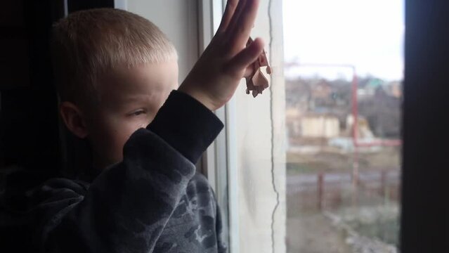 Russian attack on Ukraine. Child sits on the window and cries. Against the background of a destroyed building, cracks and devastation near. Consequences of hostilities and the shelling of civilians