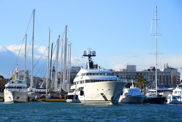 Naklejka premium Yachts and motor boats in La Marina de Valencia, Spain. Luxury yacht and fishing motorboat in yacht club at Mediterranean Sea. Skiff and Sailboat in port. Yachting and sailing sport. Quai at ​Dock.