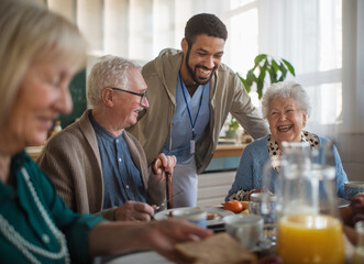 Group of cheerful seniors enjoying breakfast in nursing home care center.