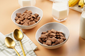 Nougat bites - sweet cocoa and hazelnut wheat puffed pillows - breakfast cereal in white bowls,...