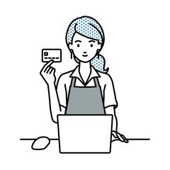 デスクで座ってPCを使いながらクレジットカードを手に持っているカフェ店員の女性
