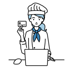 デスクで座ってPCを使いながらクレジットカードを手に持っている調理師の女性