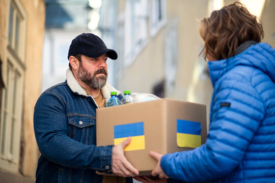 Volunteers collecting boxes with Humanitarian aid for Ukrainian immigrants in street.