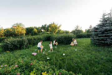 A group of adults and children together at sunset is engaged in garbage collection in the park. Environmental care, waste recycling. Sorting garbage.