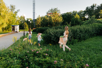 A group of adults and children together at sunset is engaged in garbage collection in the park....