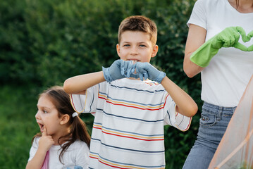 A boy and a girl show hearts after cleaning garbage in the park during sunset. Environmental care,...
