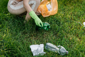 A girl in the park at sunset is engaged in garbage collection in the park. Environmental care,...