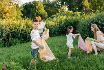 A group of adults and children together at sunset is engaged in garbage collection in the park. Environmental care, waste recycling. Sorting garbage.