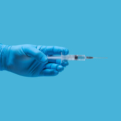 a hand in a blue medical glove with a syringe on a blue background