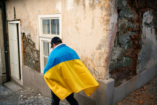 Protestor covered with blue and yellow Ukrainian flag protesting against war in Ukraine in street