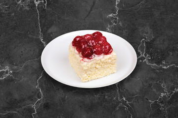 Raspberry and Cream Cake, square. It is served on a white plate, on a black background.