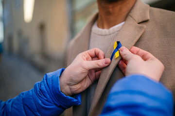 Protest organizer distributing Ukrainian blue and yellow ribbons to people protesting against war in Ukraine