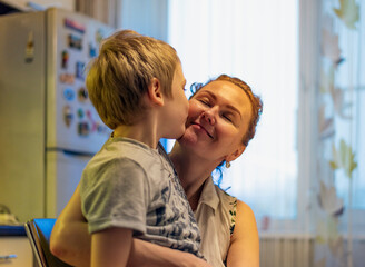 Cute little little baby, son hugging mom, hugging mom in the kitchen. Spend an evening with your family.