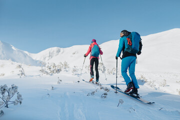 Fototapeta na wymiar Rear view of ski touring couple hiking up a mountain in the Low Tatras in Slovakia.