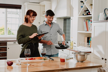 Everything has to look perfect for our blog. Shot of a couple using a digital tablet while cooking at home.