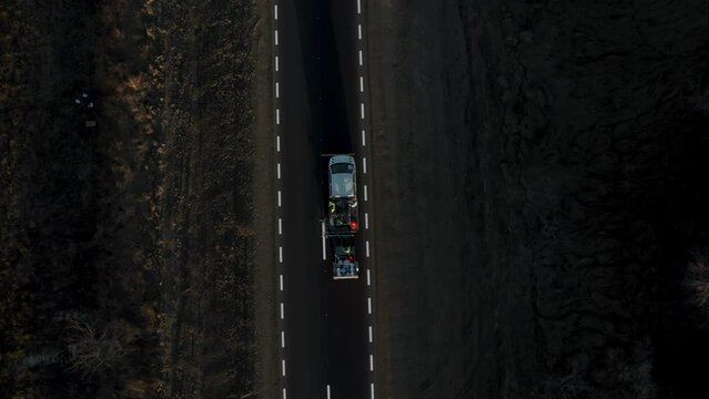 Road workers use hot-melt scribing machines to paint trafic signs on asphalt road surface outside the city. Road marking. Workers and paint sprayers for roads. Thermoplastic paint for road marking.