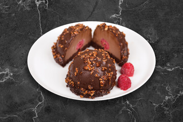 Chocolate Cake with a macaron. It is served on a white plate on a black background.