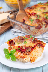 Mac and cheese with meatballs, mozzarella, tomato sauce and basil, on white plate, vertical
