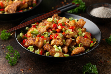 Stir fry salt and pepper pork loin with herbs in black bowl. Asian food