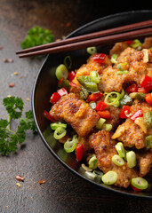 Stir fry salt and pepper pork loin with herbs in black bowl. Asian food