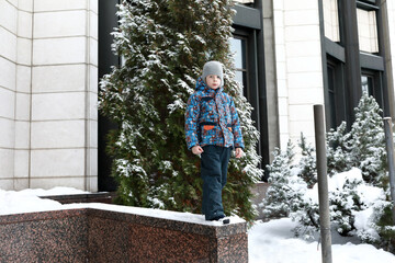 Fototapeta na wymiar Boy on curb of building in winter