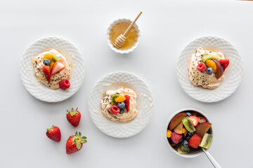 Top down view of homemade meringues topped with fresh fruit and honey.