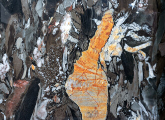 Texture of natural gray-black quartz stone with orange mineral inclusions.