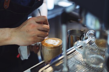Barista making coffee latte art at cafe.