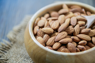 Almonds nut and wood spoon  in wood cup on wood background.