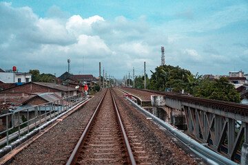 Fototapeta premium Railroad made of iron, wood and gravel in the middle of suburban settlements and over rivers in Indonesia