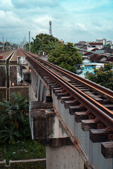 Fototapeta premium Railroad made of iron, wood and gravel in the middle of suburban settlements and over rivers in Indonesia