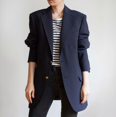 Woman wearing oversized navy blazer, striped t-shirt and black jeans isolated on white background