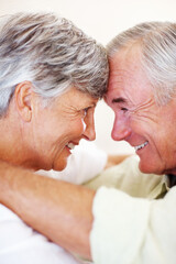 Smiling mature couple looking at each other. Closeup of affectionate mature couple smiling while looking at each other, head to head.